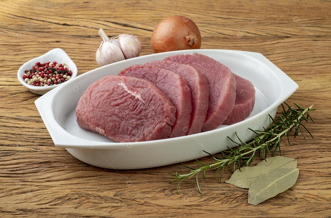 Corte de carne redonda de olho cru sobre prato branco com temperos