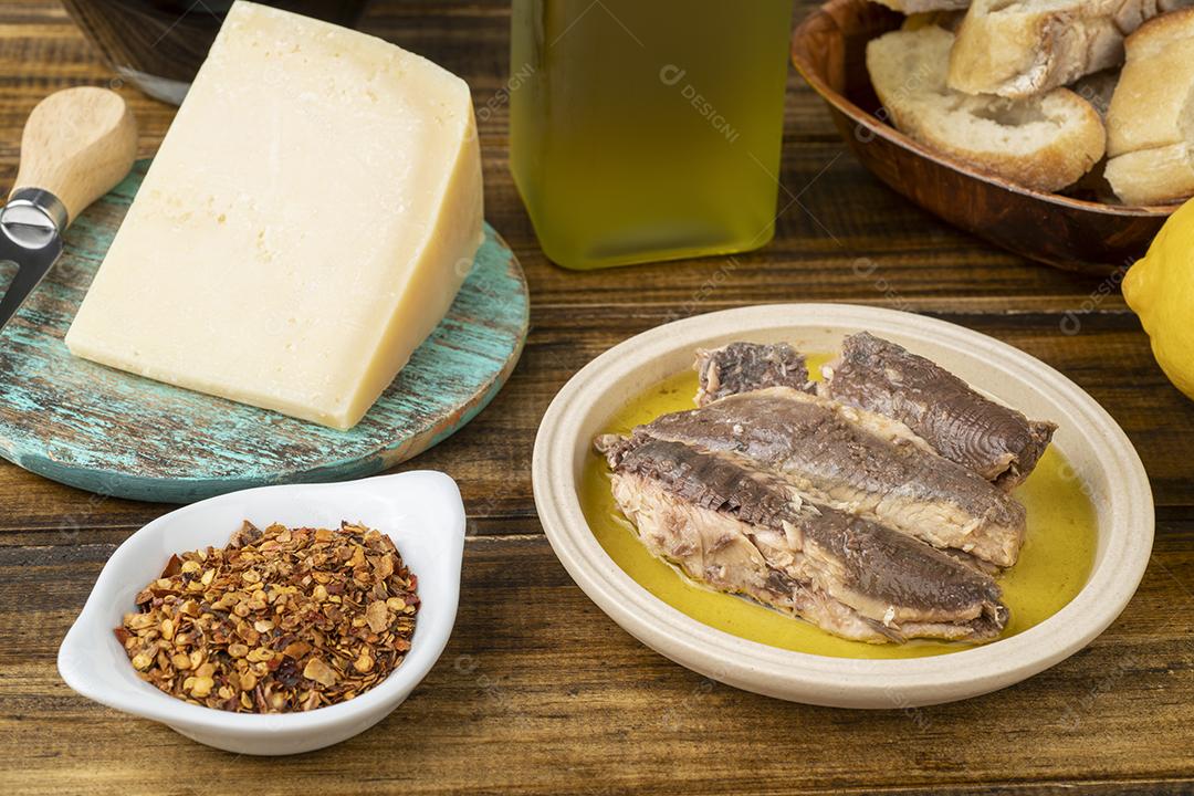 Peixe, azeite, queijo parmesão, pão e vinho sobre aba de madeira