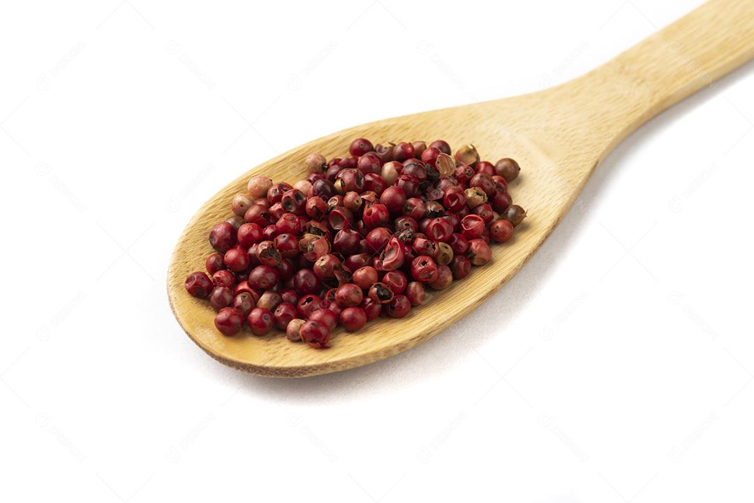 grãos de pimenta vermelha seca em uma colher de madeira isolado