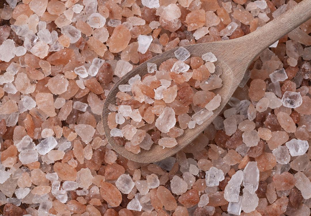 Sal rosa do Himalaia em uma colher sobre mesa de madeira