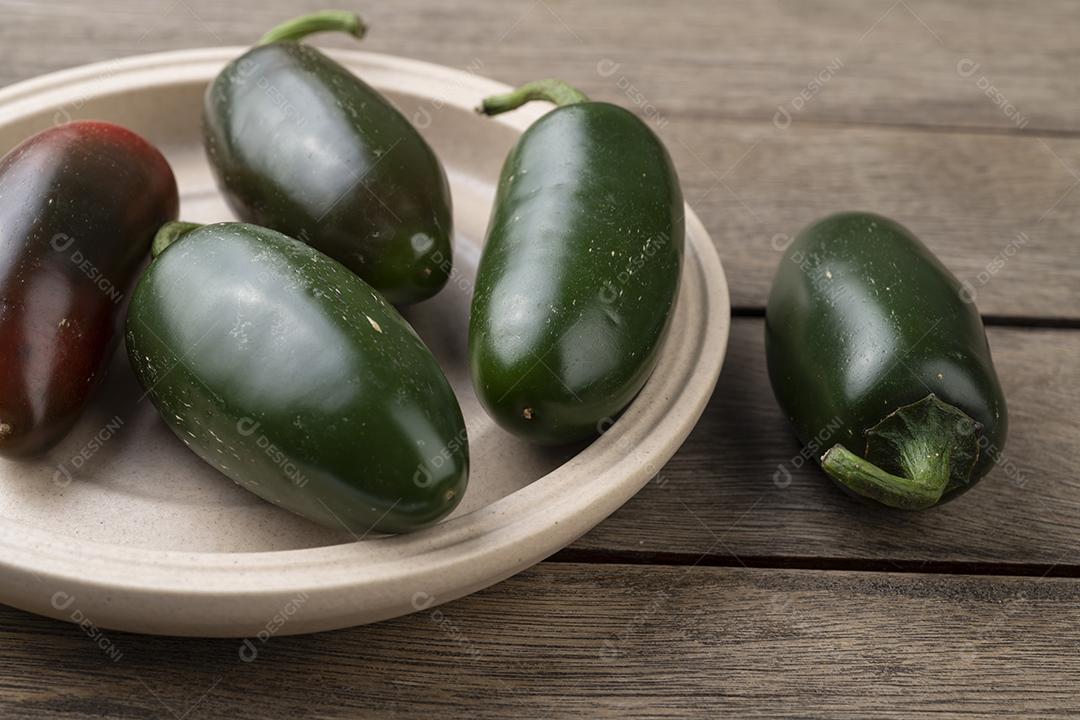 Pimentas jalapeno verdes em um prato sobre mesa de madeira