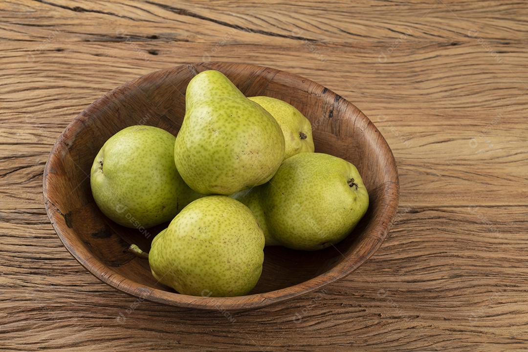 Peras verdes em uma tigela sobre mesa de madeira