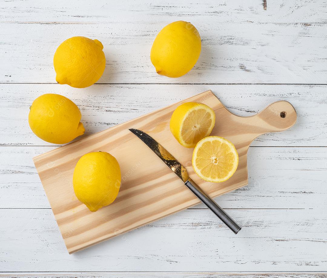 Limões sicilianos e metades de frutas sobre tábua de madeira