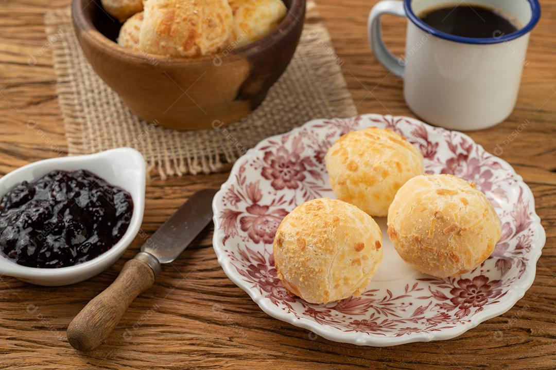 Pão de queijo típico brasileiro em uma cesta, café, geleia e manteiga