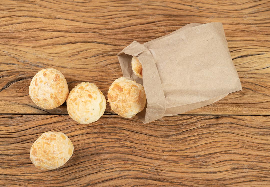 Pães típicos de queijo brasileiro em um saco de papel sobre mesa de madeira