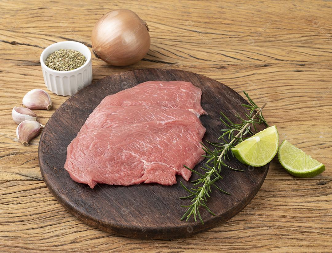 Carne de bife de alcatra sobre tábua de madeira com temperos