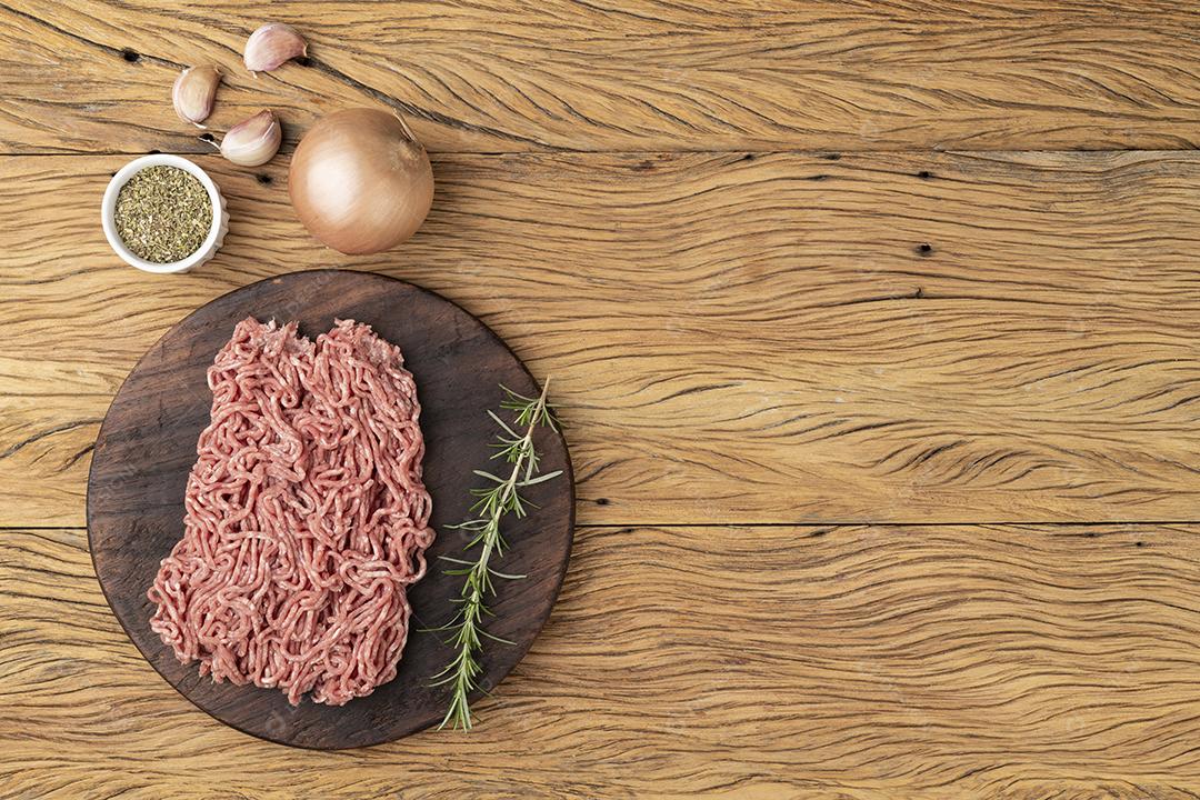 Carne moída sobre tábua de madeira com temperos