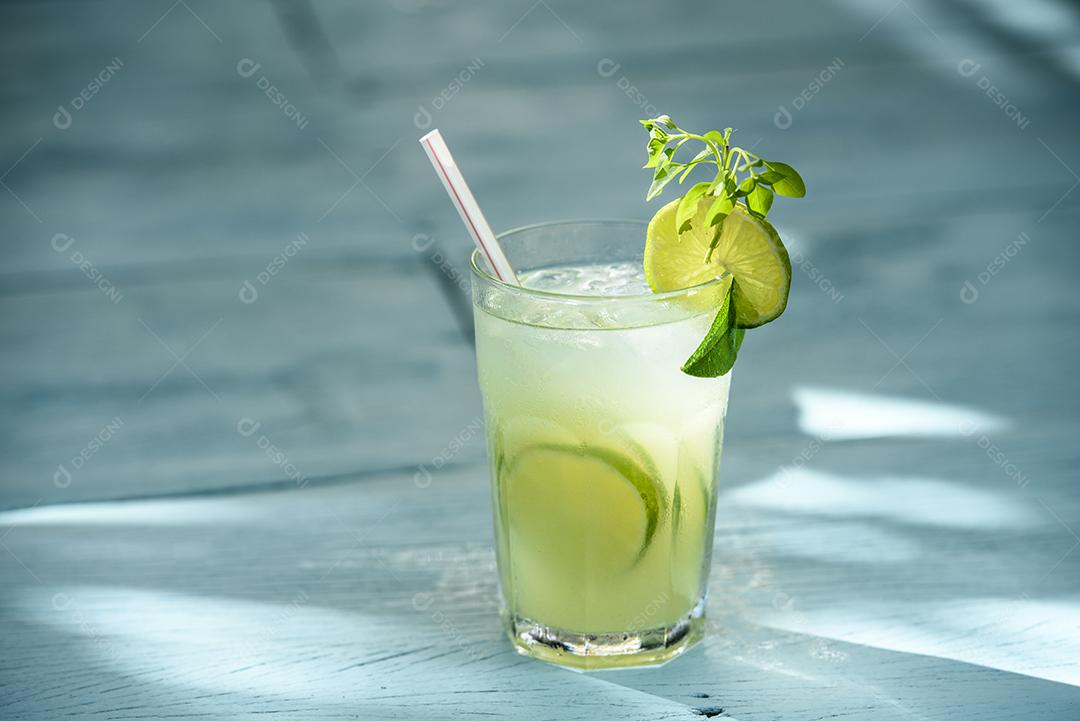Caipirinha bebe com limão em uma mesa de madeira azul. Bebida típica brasileira feita com cachaça, limão, gelo e açúcar