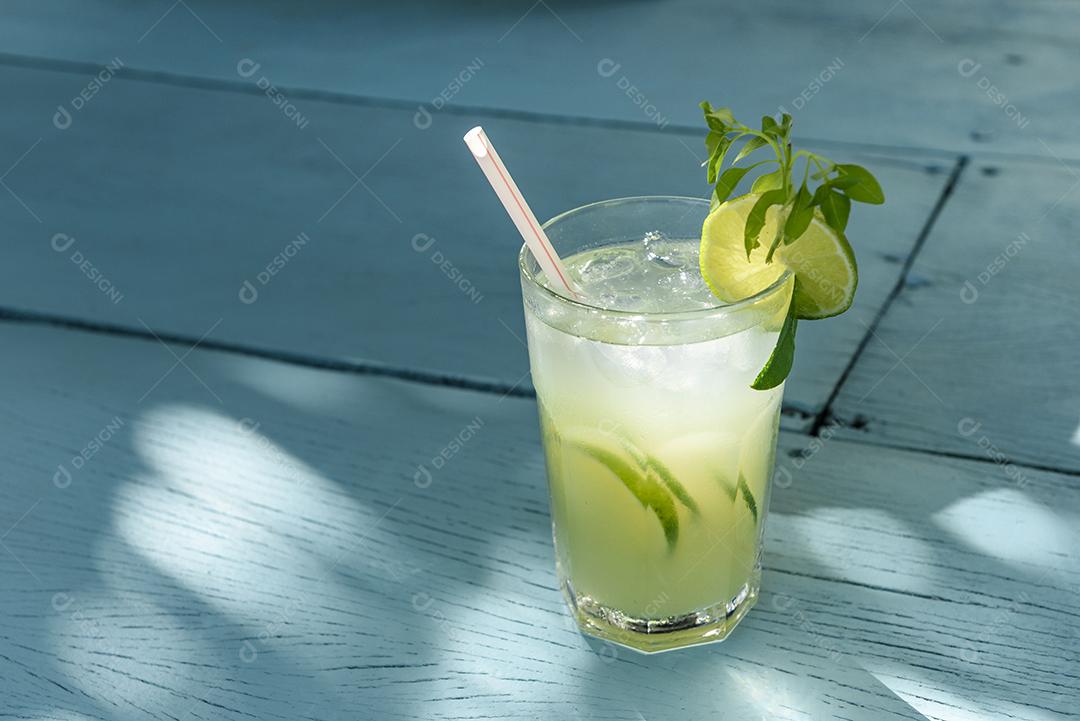 Caipirinha bebe com limão em uma mesa de madeira azul. Bebida típica brasileira feita com cachaça, limão, gelo e açúcar