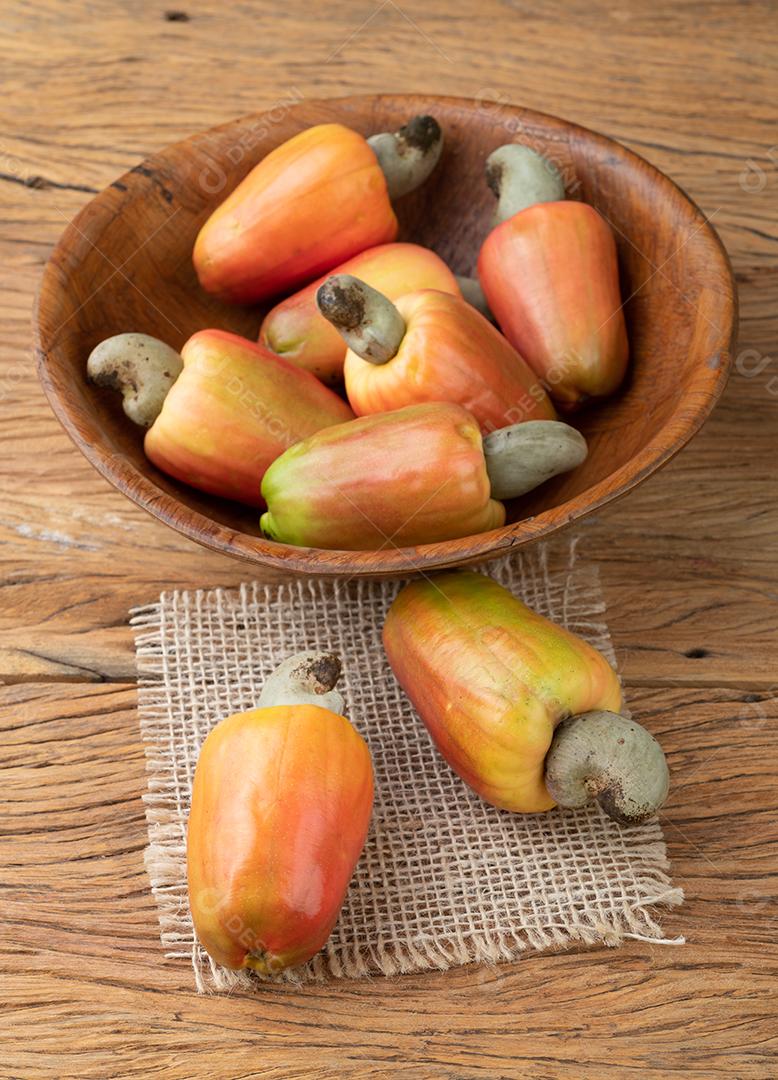 Um grupo de frutas de caju em uma tigela sobre mesa de madeira