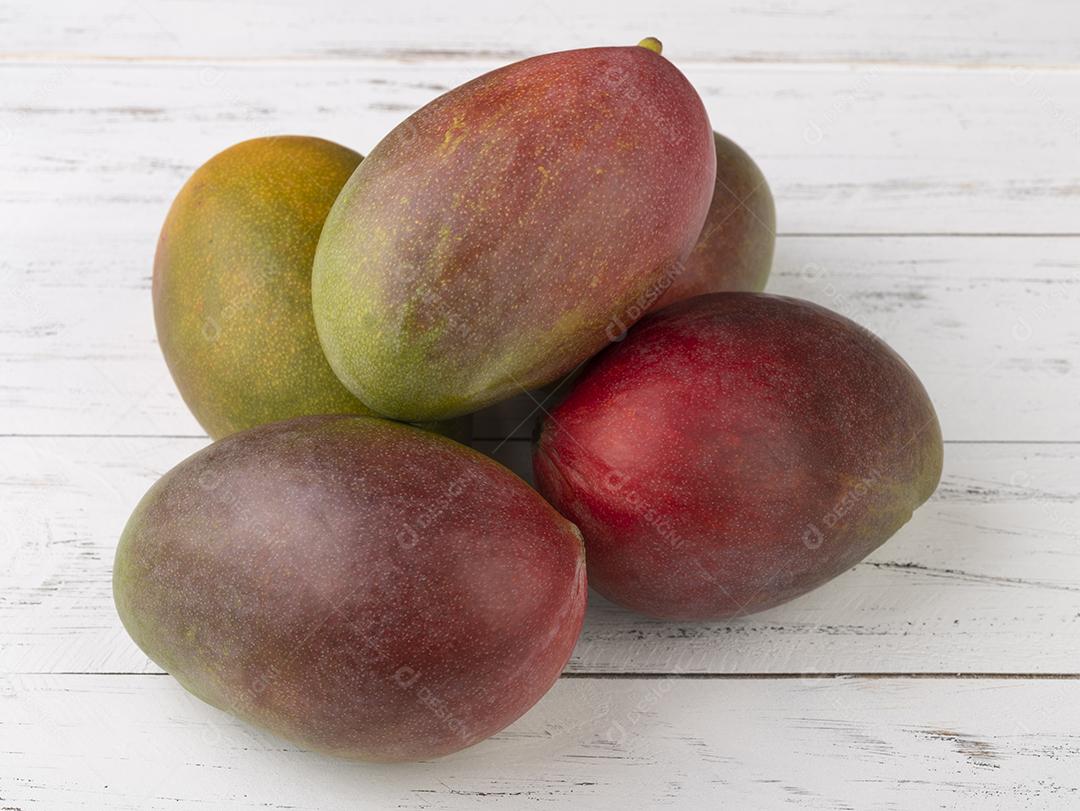 Um grupo de mangas maduras sobre mesa de madeira branca