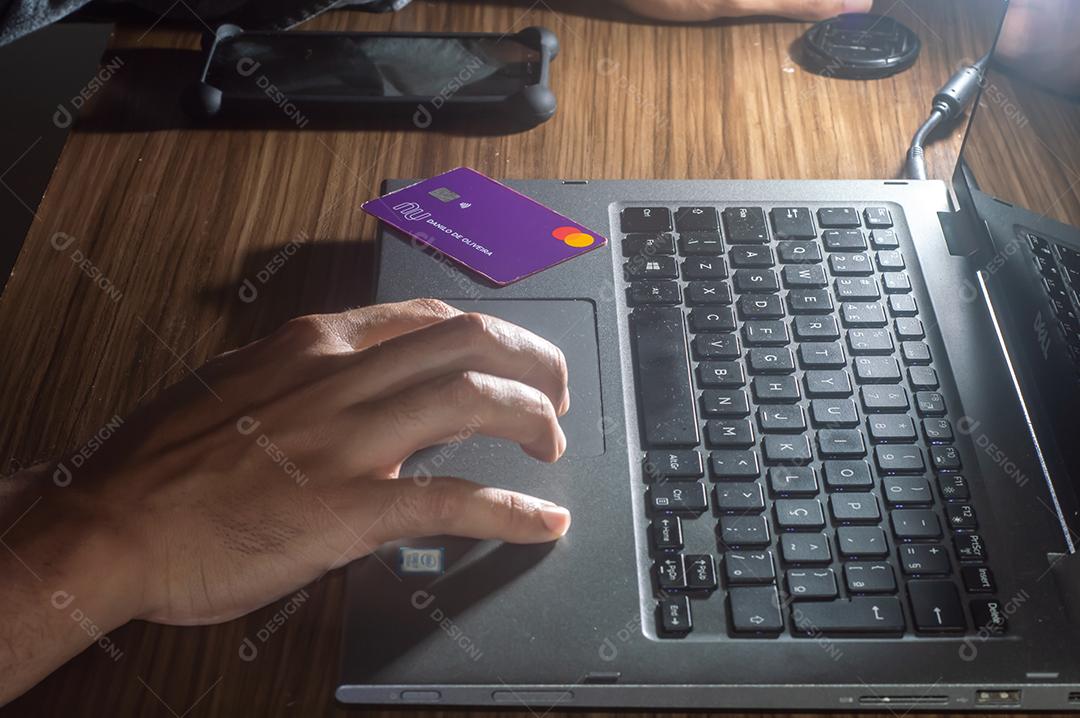 Cartão nubank perto de um notebook da marca dell com digitação manual