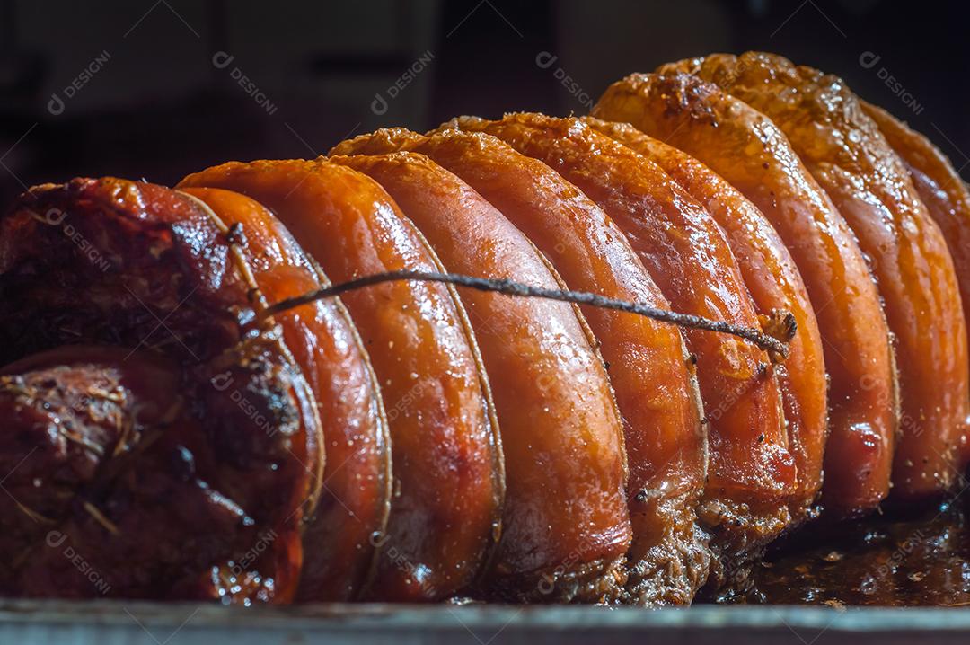 Porchetta inteira assada e defumada, com casca avermelhada, colocada em uma assadeira