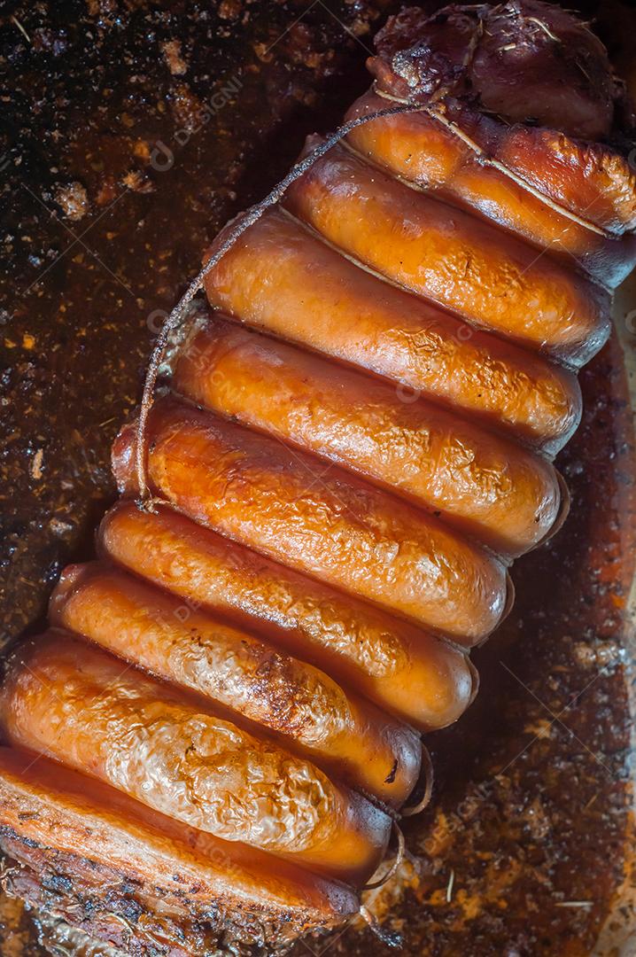 Porchetta inteira assada e defumada, com casca avermelhada, colocada em uma assadeira