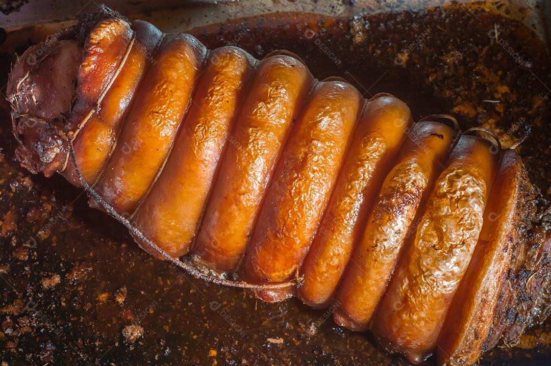 Porchetta inteira assada e defumada, com casca avermelhada, colocada em uma assadeira