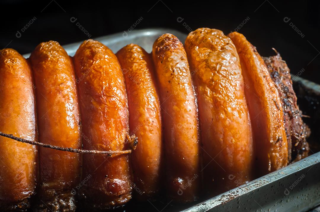 Porchetta inteira assada e defumada, com casca avermelhada, colocada em uma assadeira