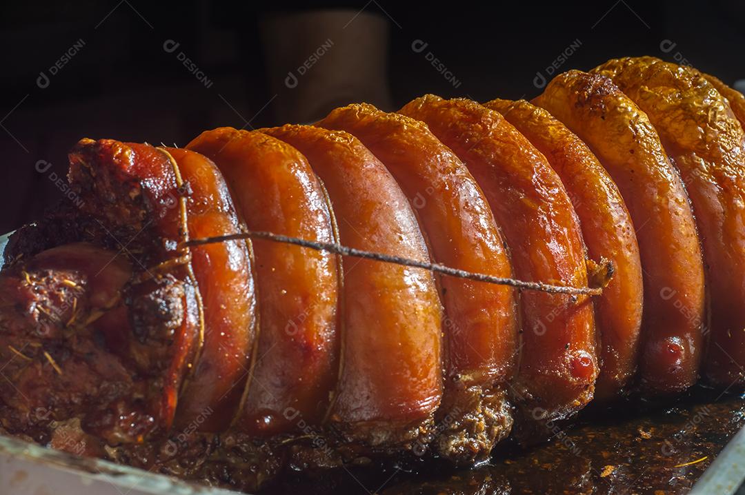 Porchetta inteira assada e defumada, com casca avermelhada, colocada em uma assadeira