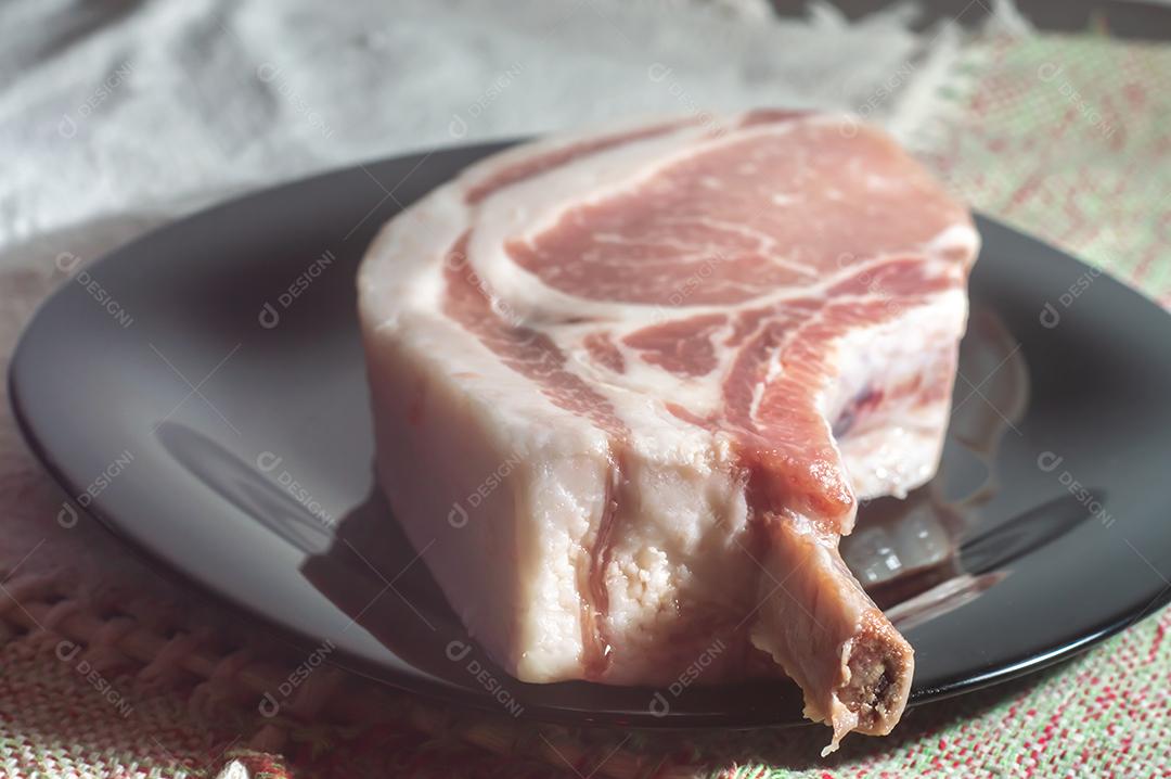 Bifes de osso de carne de porco crua Bifes de porco Tomahawk na chapa preta, vista aérea. Três bifes de porco crus, prontos para grelhar vista superior..