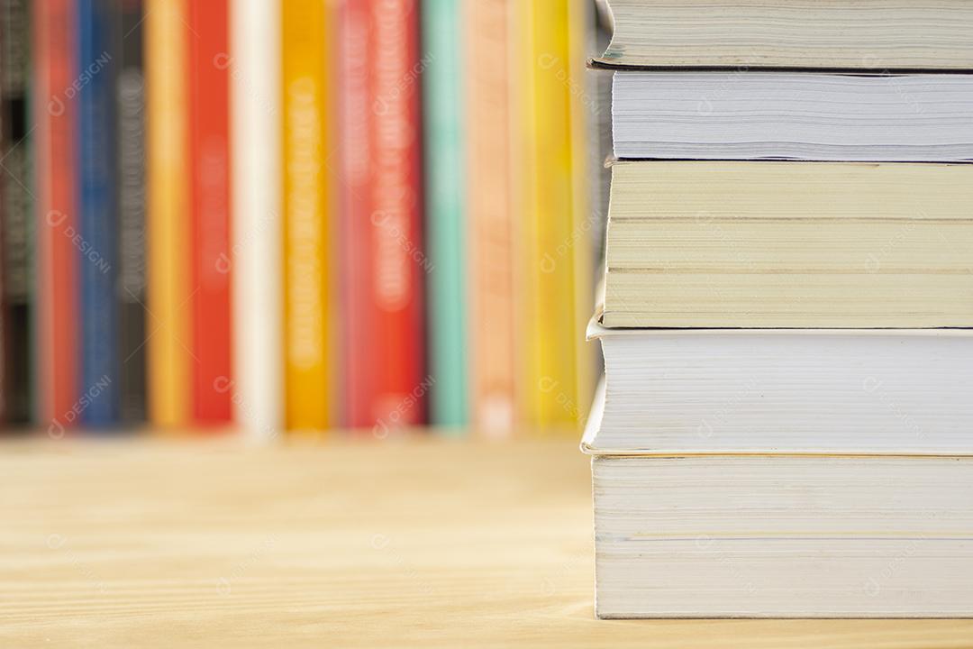 Stack of books in front of books on a wooden table