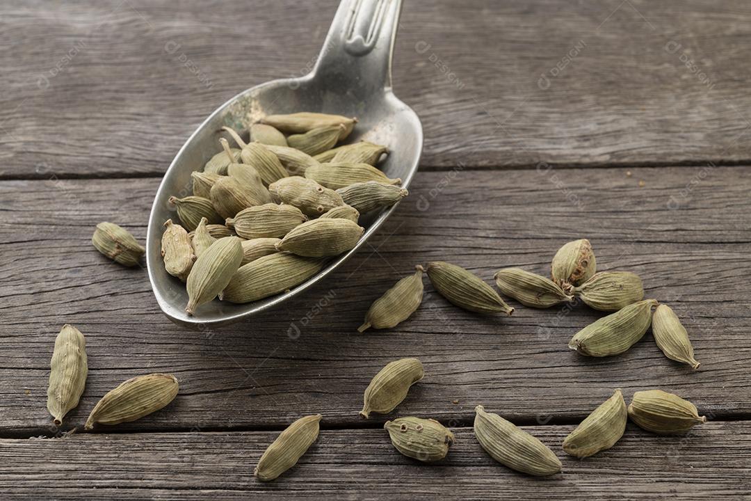 Sementes de cardamomo em uma colher  sobre a mesa de madeira