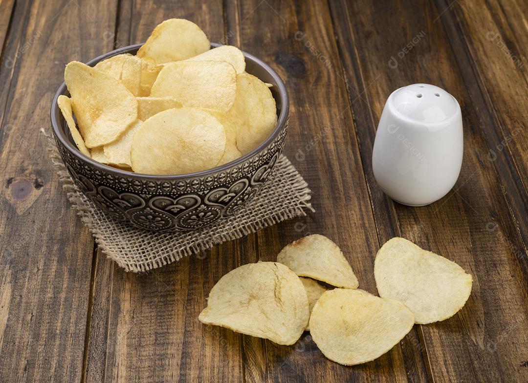 Batatas fritas em uma tigela com sal sobre a mesa de madeira