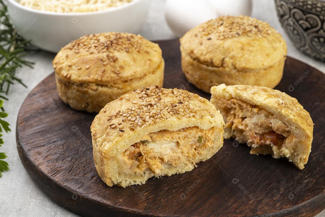 Tortas de frango caseiras sobre tábua de madeira com ingredientes