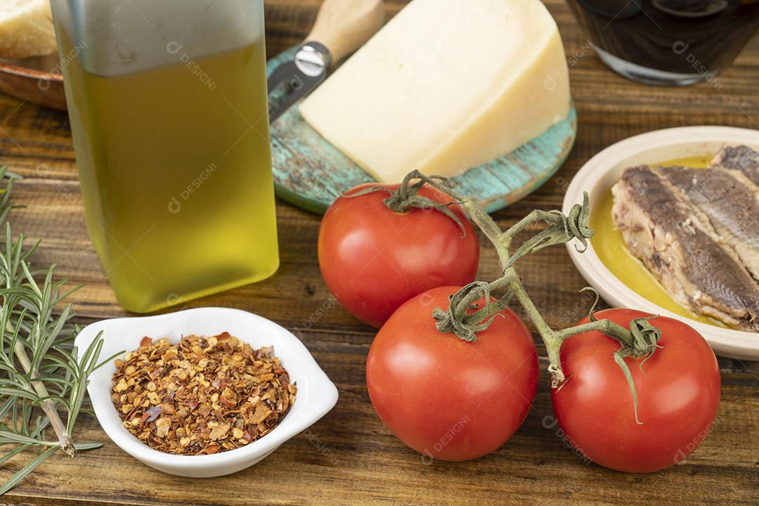 Tomates, peixes, azeite, vinho, queijo parmesão e ervas sobre