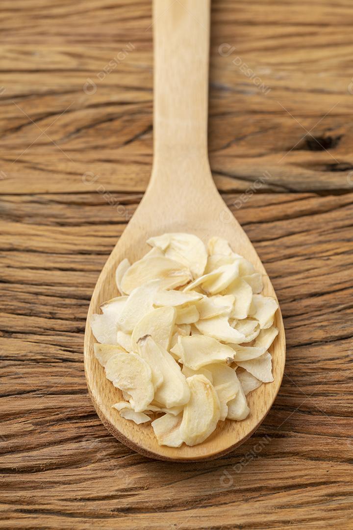 fatias de alho seco em uma colher de madeira. Pano de fundo alimentar
