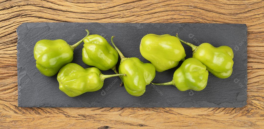 Pimentas verdes cambuci em uma tábua de pedra sobre mesa de madeira. Tipica