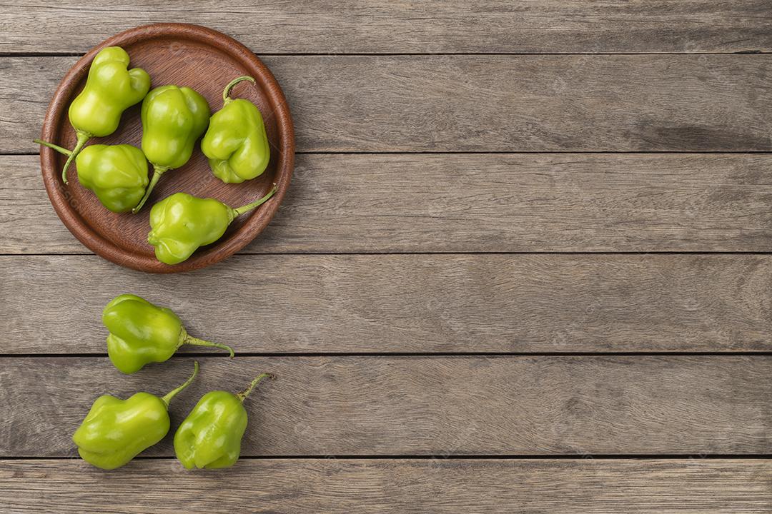 Pimentas verdes cambuci em um prato sobre mesa de madeira