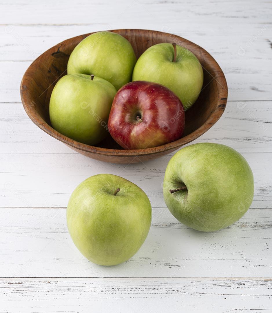 Maçãs verdes e vermelhas em uma tigela sobre mesa de madeira branca