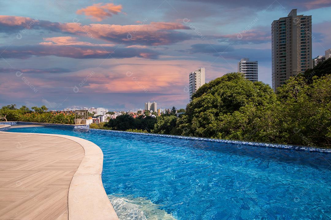 Piscina infinita com árvores e edifícios ao fundo