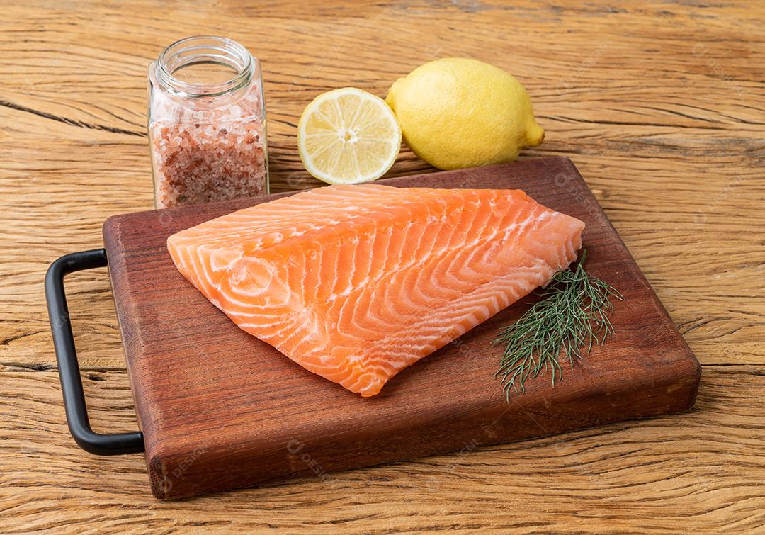 Filé de salmão cru com temperos sobre tábua de madeira