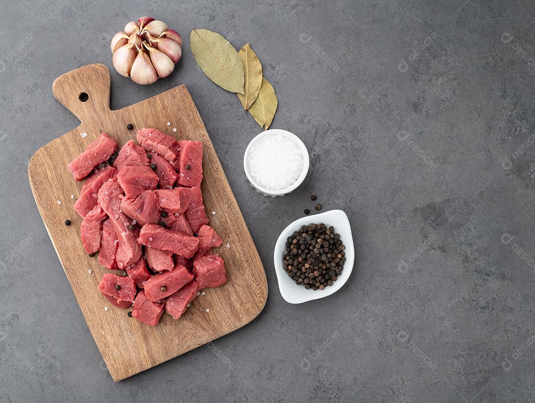 Carne de cima picada em tábua de madeira sobre fundo de pedra