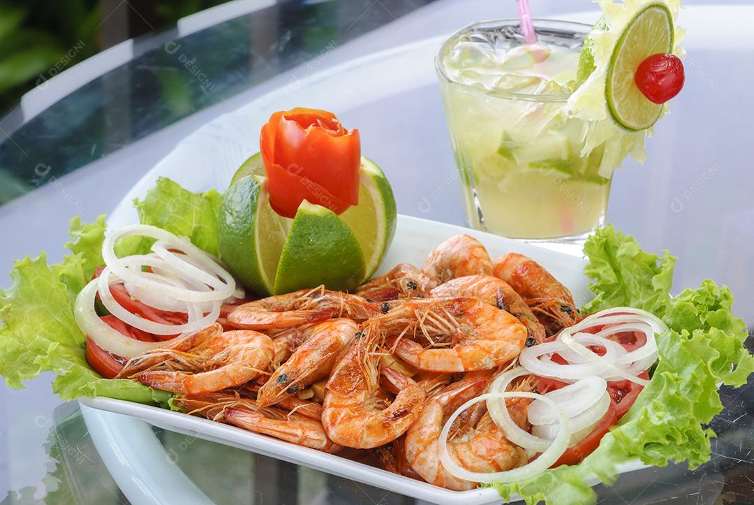 Camarão em alho e óleo com bebida brasileira de caipirinha.