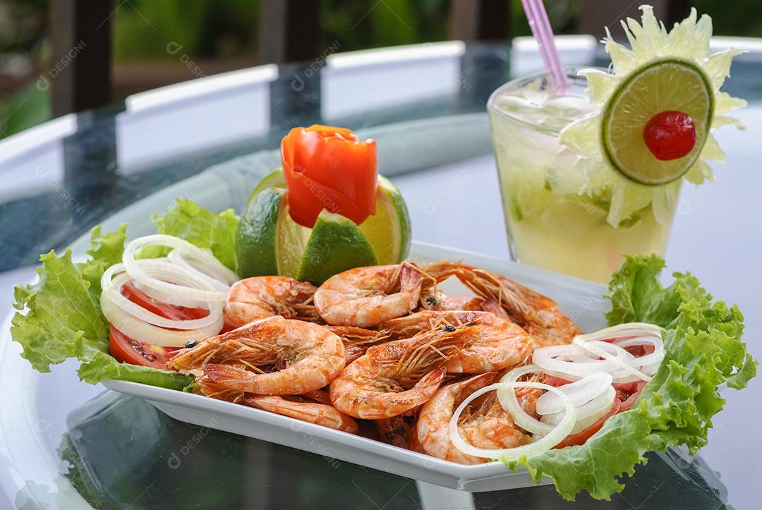 . Camarão em alho e óleo com bebida brasileira de caipirinha.