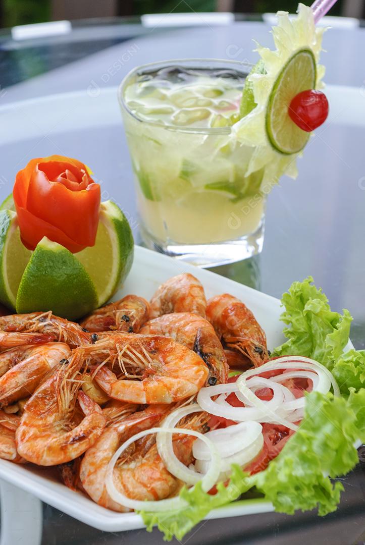 Camarão. Camarão em alho e óleo com bebida brasileira de caipirinha.