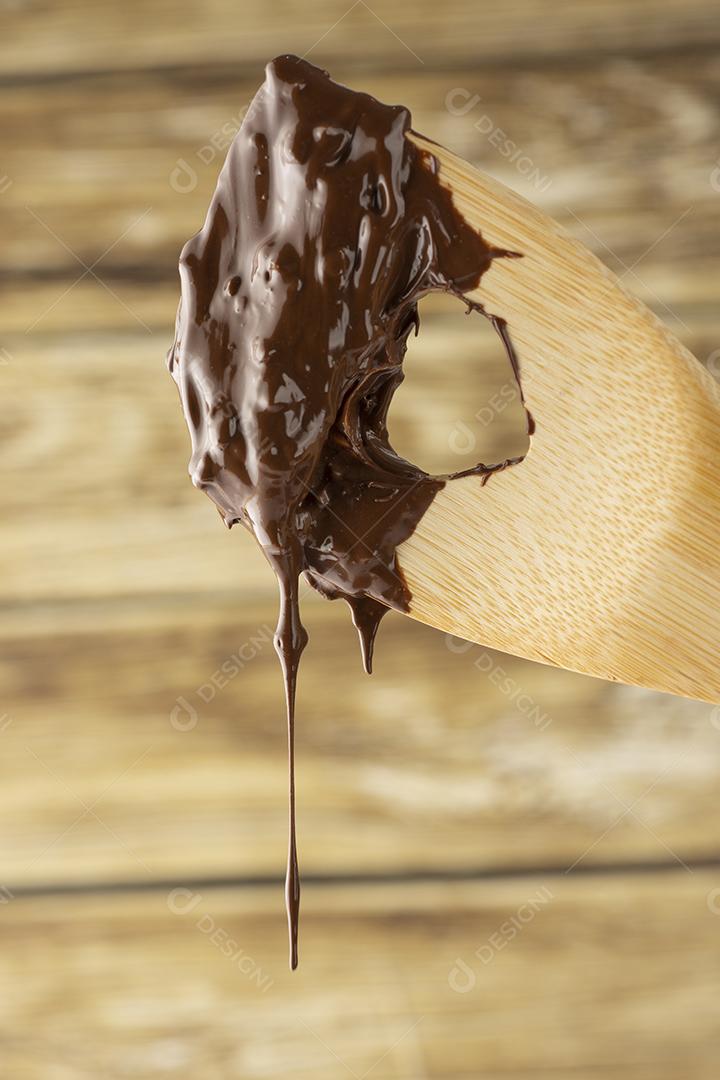 Chocolate derretido caindo de uma colher de madeira