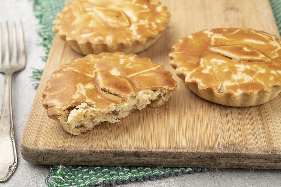 Tortas caseiras de frango recheado sobre tábua de madeira