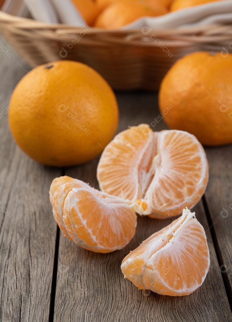 Tangerinas com frutas cortadas sobre mesa de madeira