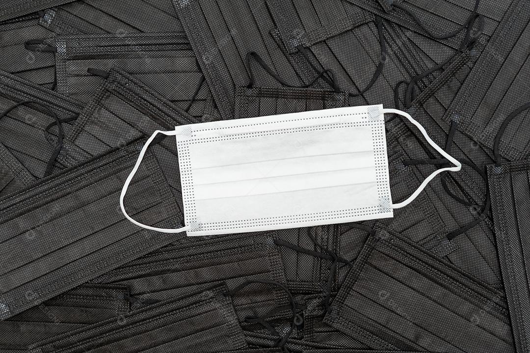 Máscara médica branca fundo de máscaras médicas pretas espalhadas Proteção contra o COVID-19.