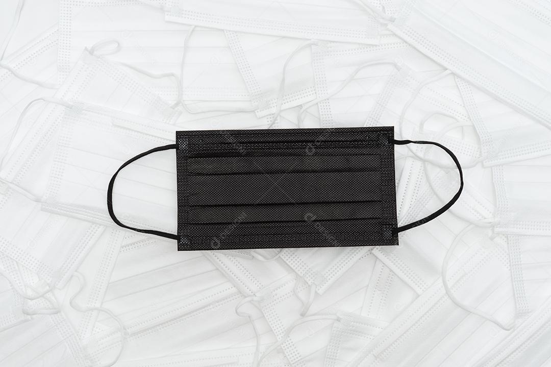 Máscara médica preta com fundo de máscaras médicas brancas espalhadas.