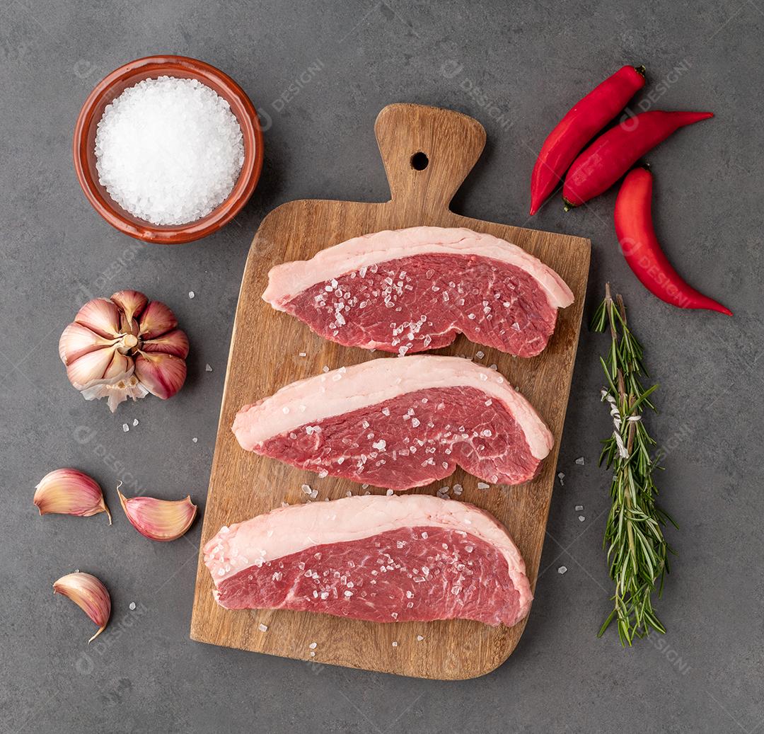 Picanha crua fatiada ou carne de alcatra sobre tábua de madeira com tempero