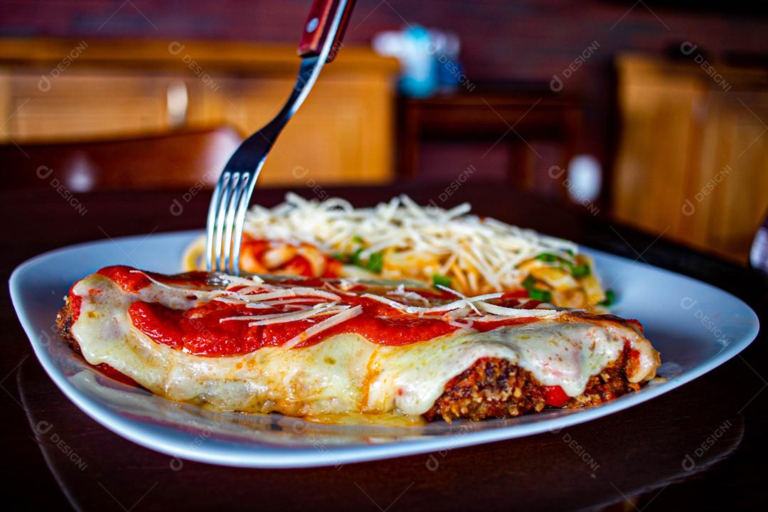 Comida Frango à parmegiana sobre prato branco