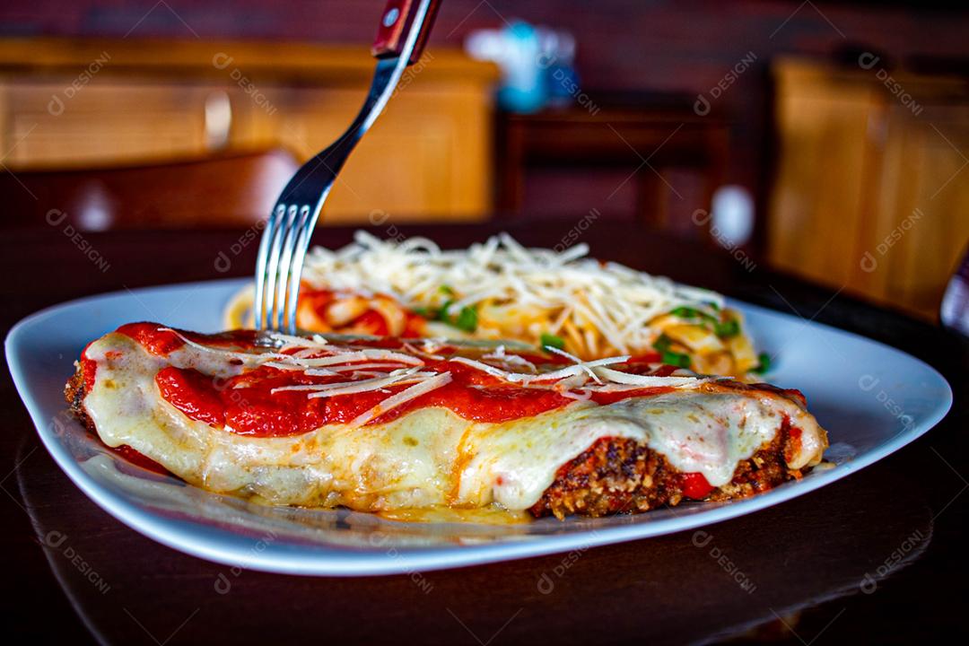 Comida Frango à parmegiana sobre prato branco