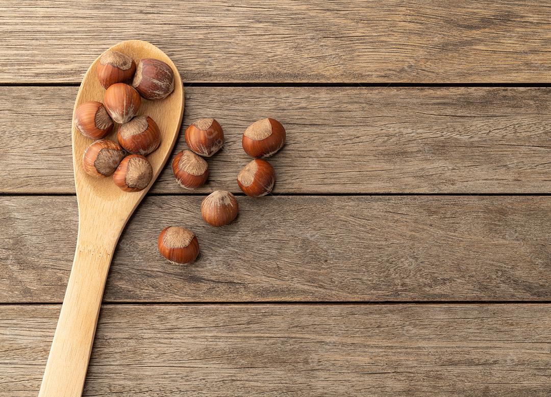 Avelãs sem casca em uma colher sobre a mesa de madeira