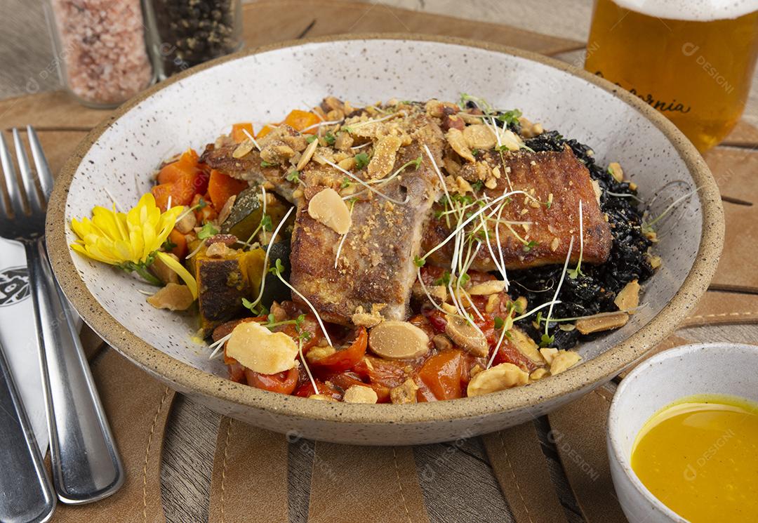 Peixe grelhado, arroz preto e legumes.