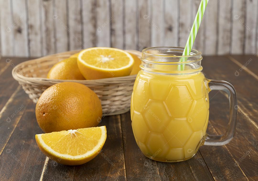 Suco de laranja com laranja fatiada sobre uma mesa de madeira