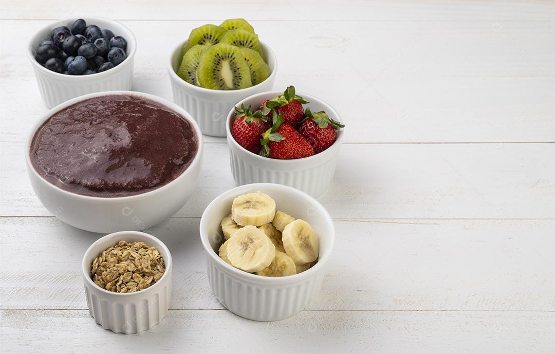 Tigela típica de açaí brasileira com frutas e muesli sobre madeira