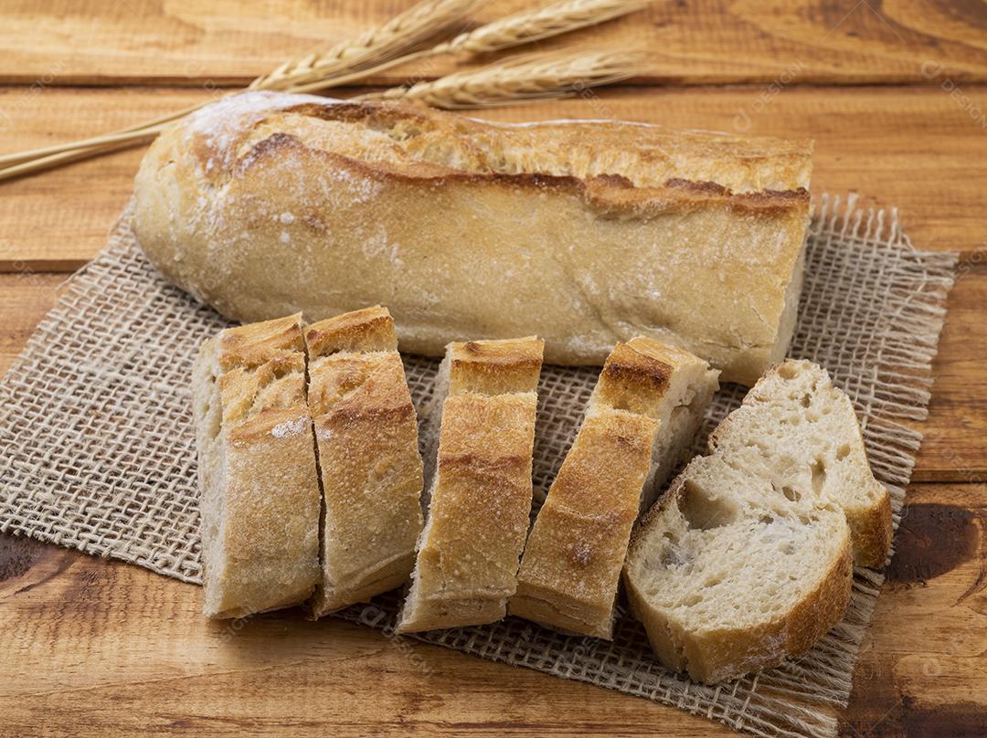 Tradicional pão de baguete francês caseiro com fatias sobre madeira